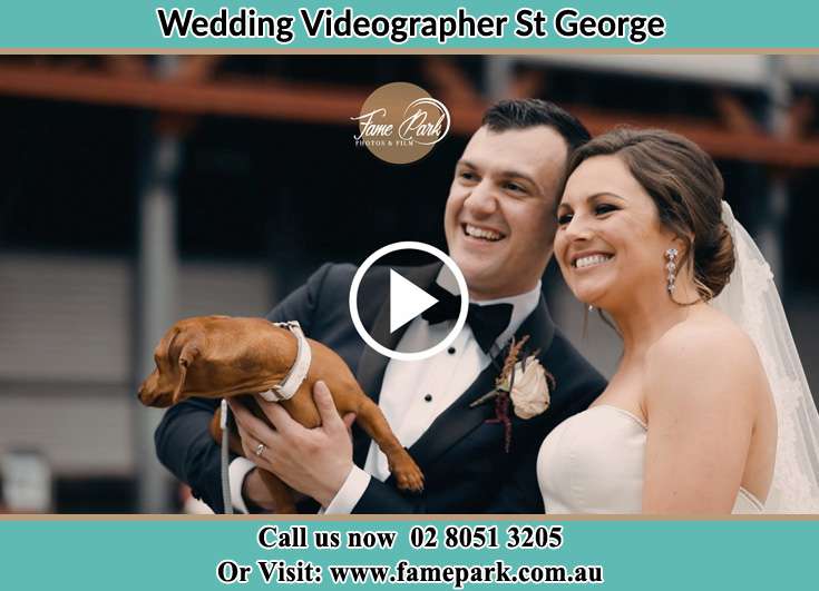 The Groom and the Bride smiling while carrying their dog St George